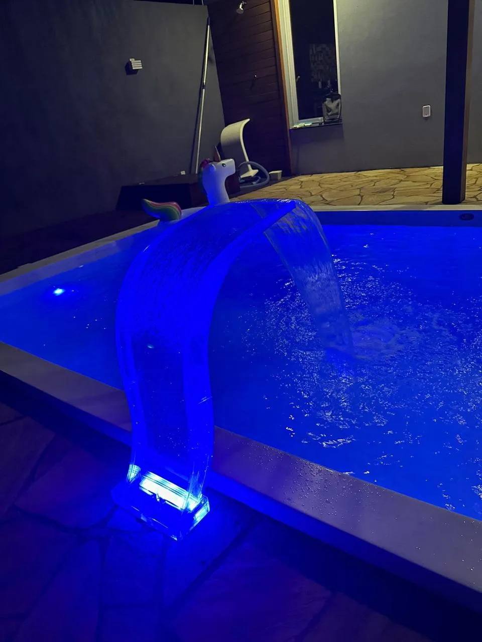 Piscina e cascata com iluminação azul à noite