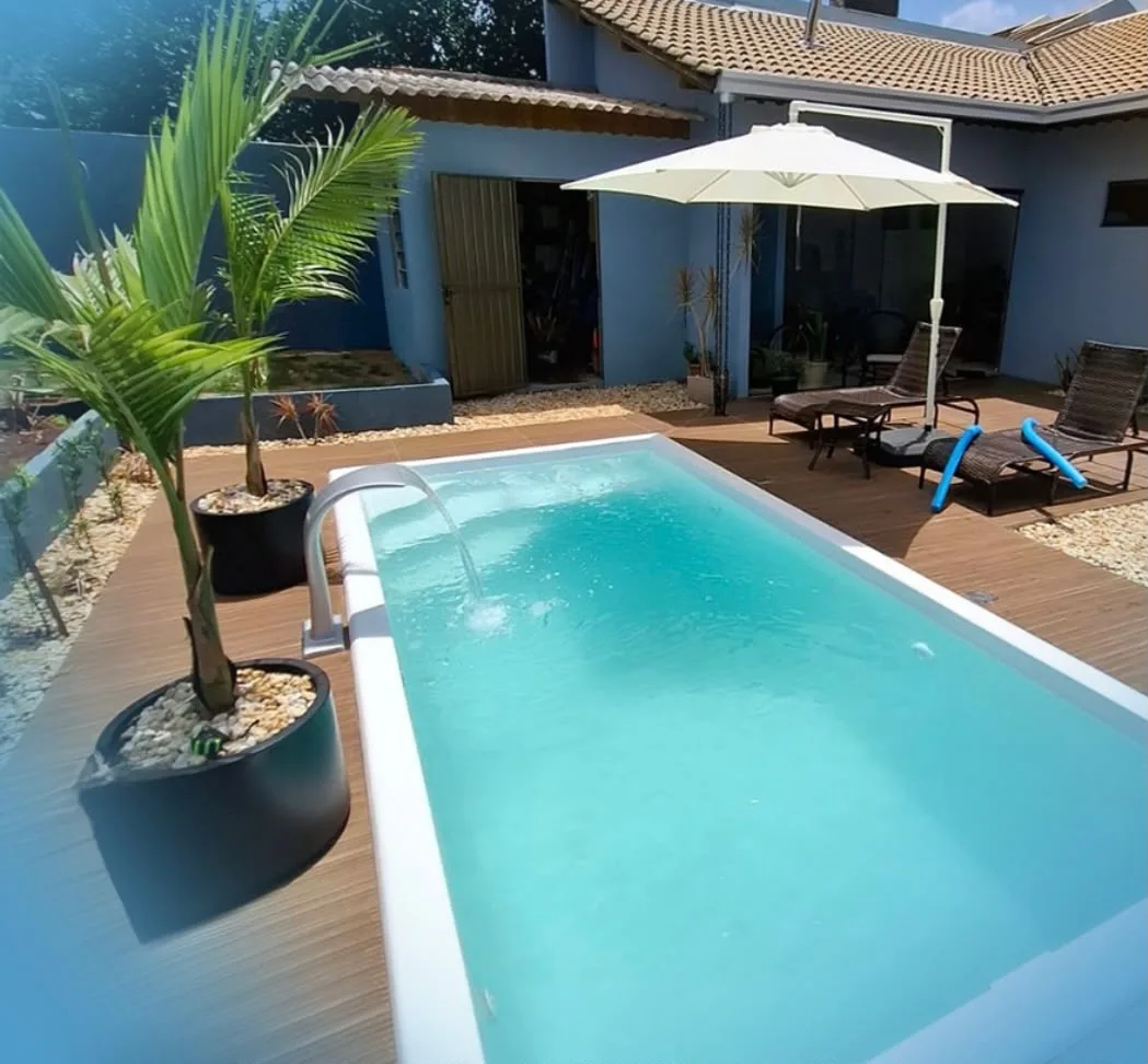 Piscina com cascata ao lado de palmeiras e espreguiçadeiras